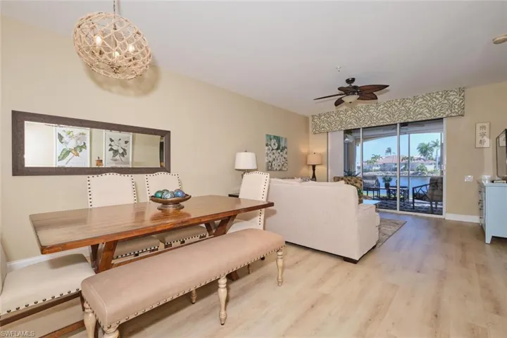 Dining room with light wood-type flooring and ceiling fan with notable chandelier