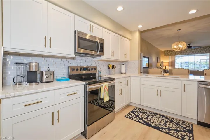 Kitchen with sink, white cabinets, stainless steel appliances, and tasteful backsplash