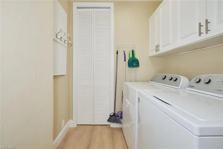 Laundry area featuring cabinets, light hardwood / wood-style flooring, and washing machine and clothes dryer