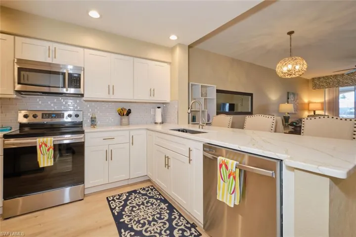 Kitchen with kitchen peninsula, sink, white cabinets, and appliances with stainless steel finishes