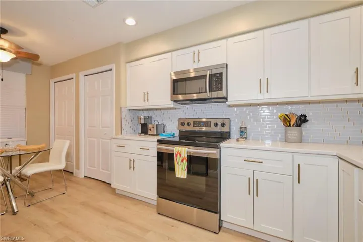 Kitchen with white cabinets, stainless steel appliances, and decorative backsplash