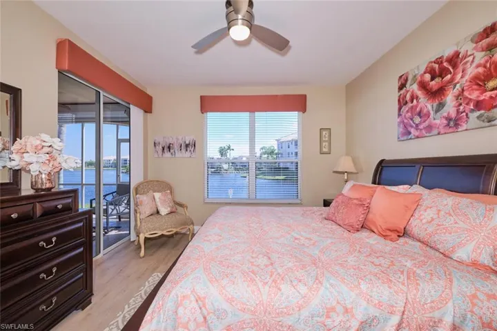 Bedroom with access to exterior, a water view, ceiling fan, and multiple windows