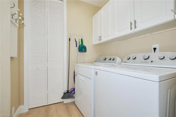 Clothes washing area featuring light hardwood / wood-style floors, cabinets, and washer and clothes dryer