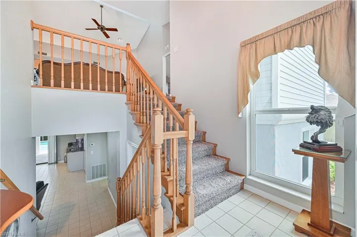 Staircase featuring tile patterned flooring, ceiling fan, and a wealth of natural light