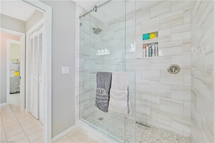 Bathroom featuring tile patterned flooring, electric water heater, and a shower with shower door