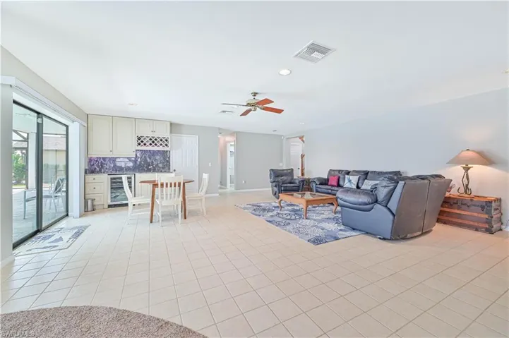 Tiled living room featuring ceiling fan and wine cooler
