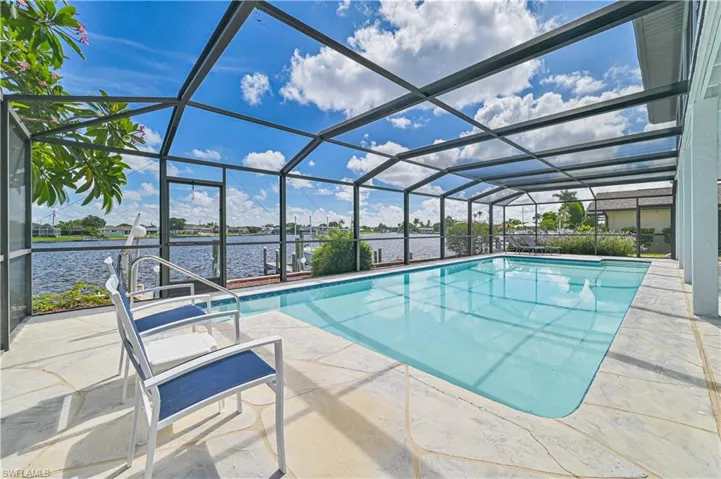 View of pool with a lanai, a patio area, and a water view
