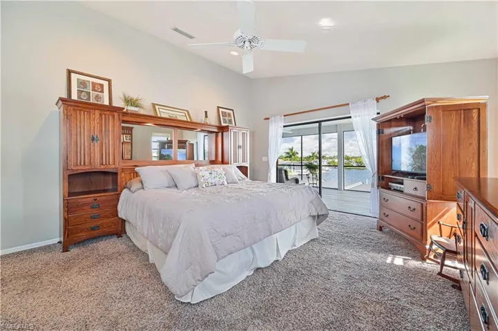 Bedroom featuring access to exterior, ceiling fan, light carpet, and high vaulted ceiling