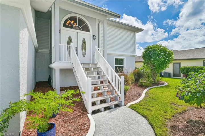 Property entrance featuring central AC unit and a lawn