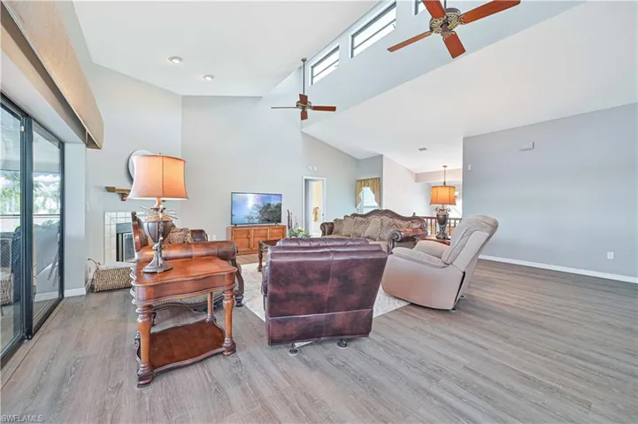 Living room featuring light wood-type flooring, ceiling fan, and high vaulted ceiling