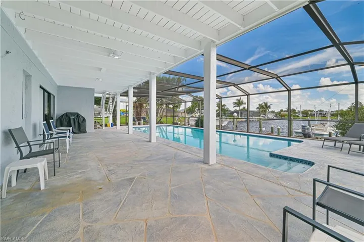 View of pool with a water view, a lanai, a grill, and a patio area