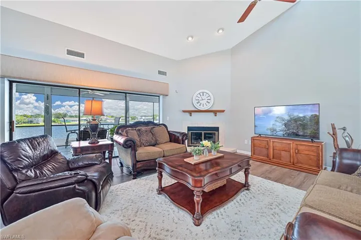 Living room with light hardwood / wood-style flooring, ceiling fan, and high vaulted ceiling