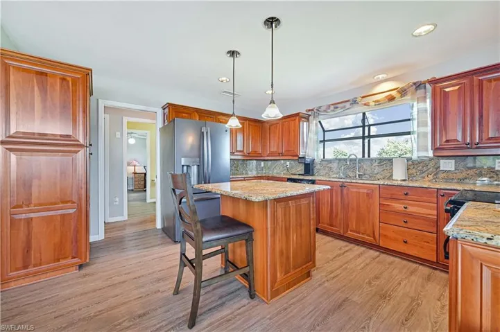 Kitchen featuring light stone counters, a kitchen island, backsplash, and light hardwood / wood-style floors