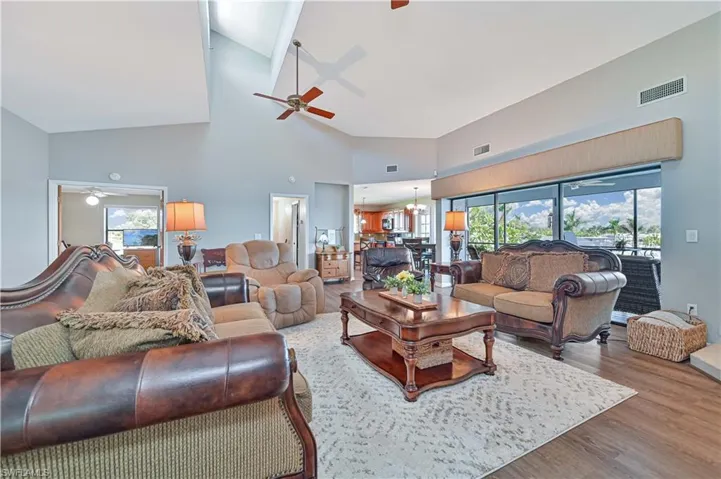Living room featuring high vaulted ceiling, ceiling fan with notable chandelier, and hardwood / wood-style flooring