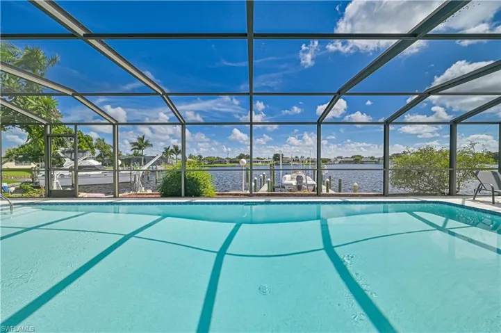View of swimming pool featuring glass enclosure and a water view