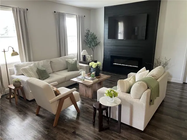 Living space featuring dark wood-finish flooring, a contemporary black shiplap accent wall, and an electric fireplace with a linear firebox