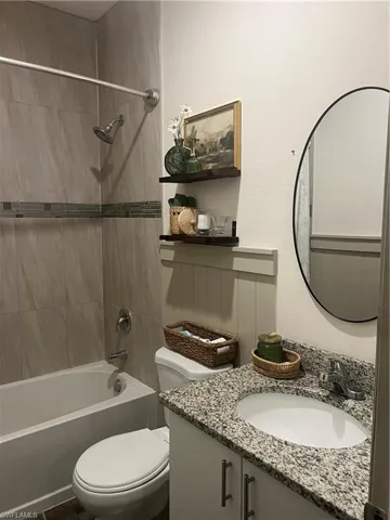 Bathroom featuring a white bathtub, ceramic wall tiles with a decorative accent band, and a shower fixture