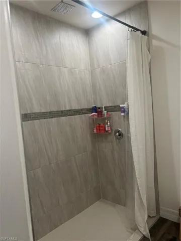 Tiled shower stall featuring a rainfall showerhead, recessed lighting, and an accent tile band