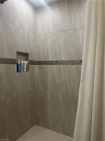 Shower with large format stone-look tile, mosaic accent band, recessed niche, and light-colored shower pan