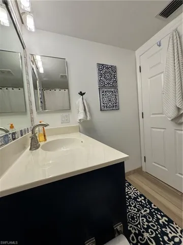 Full bath featuring wood finished floors, vanity, and visible vents