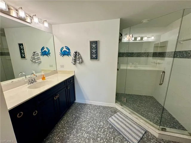 Bathroom featuring a shower stall, baseboards, vanity, and tile patterned floors