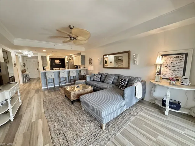 Living area with crown molding, light wood-style flooring, and ceiling fan