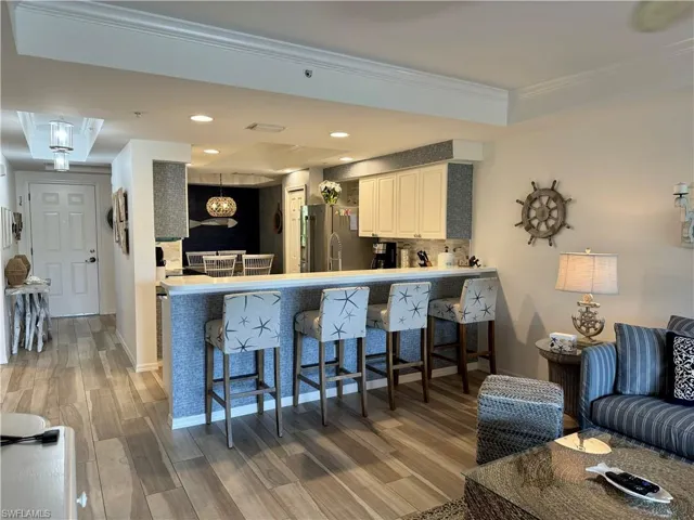 Kitchen with a breakfast bar, wood finished floors, stainless steel fridge, and crown molding