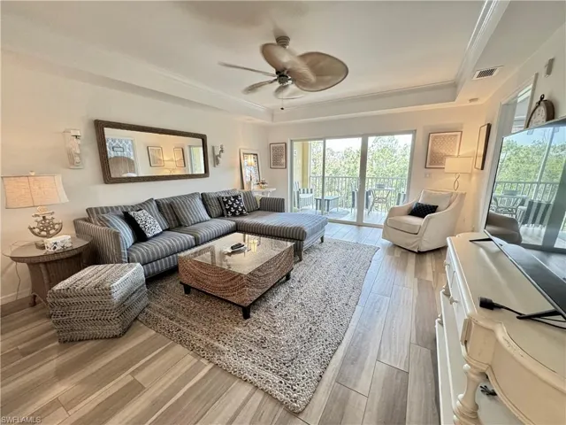 Living area featuring a wealth of natural light, visible vents, a ceiling fan, and a raised ceiling