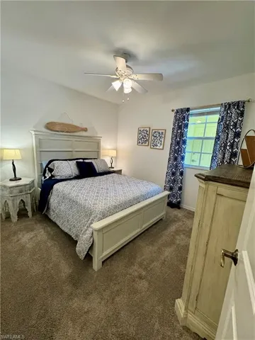 Bedroom with ceiling fan and dark colored carpet