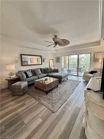 Living room with a textured ceiling, ceiling fan, and wood finished floors