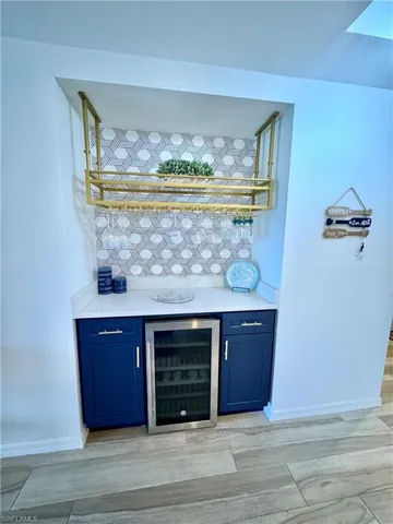 Bar featuring baseboards, tasteful backsplash, wine cooler, and a dry bar