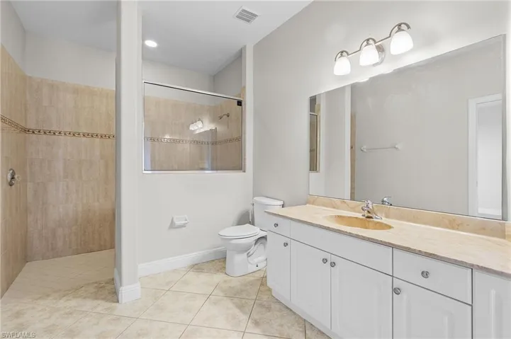 Second master bathroom with vanity, toilet, a tiled walk-in  shower, and tile patterned flooring.