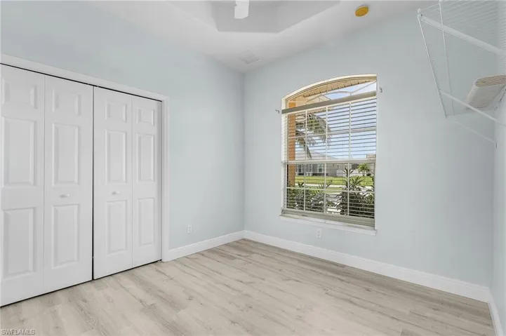 Guest bedroom with double tray ceiling and vinyl plank floor.