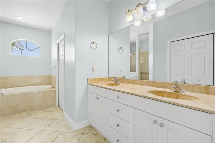 Master bathroom with dual sinks, separate shower and tub, tile patterned floors and separate commode area.