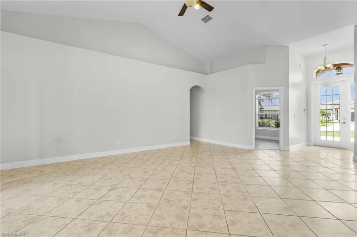 Tiled great room with ceiling fan and high cathedral ceiling.