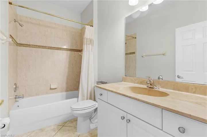 Full guest bathroom with tile patterned flooring, vanity, toilet, and shower / bath combo with shower curtain