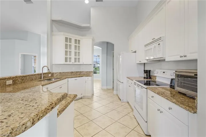 Kitchen with white cabinetry, pantry, sink and garbage disposal.