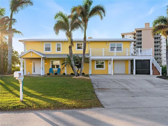View of front of house with a balcony, a garage, and a front lawn