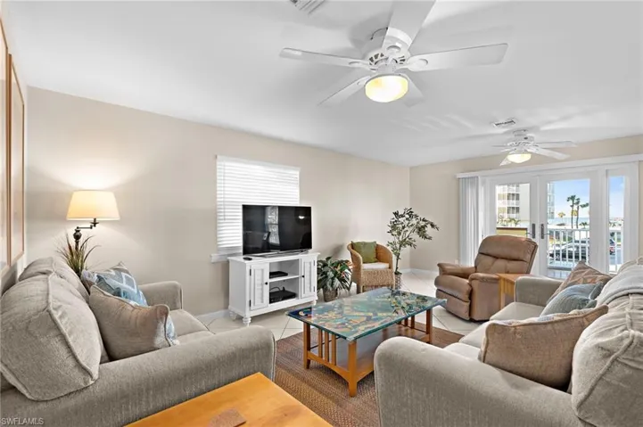Tiled living room with ceiling fan and french doors