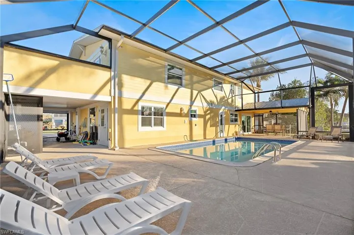 View of pool featuring glass enclosure and a patio area