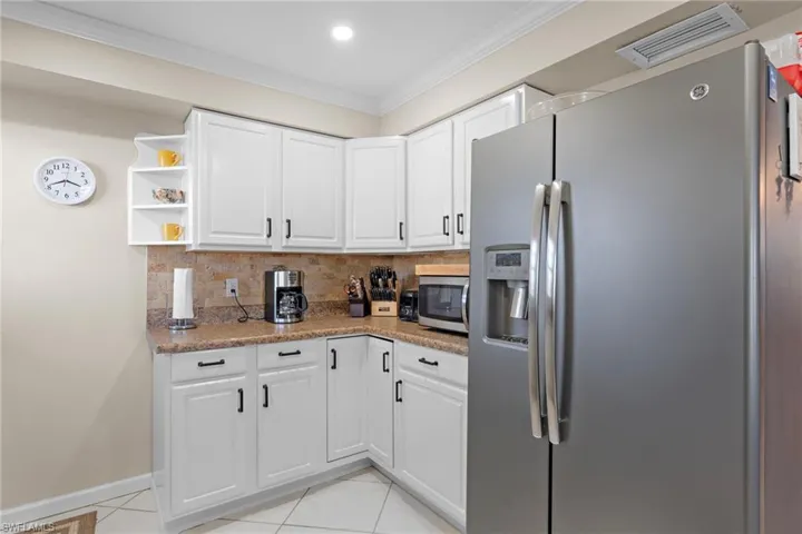 Kitchen with white cabinets, stone countertops, light tile patterned floors, and appliances with stainless steel finishes