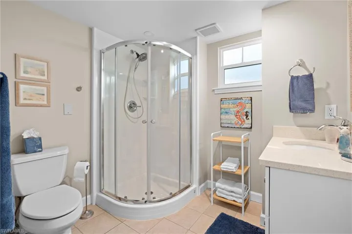 Bathroom with tile patterned flooring, vanity, toilet, and a shower with shower door