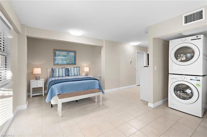 Tiled bedroom featuring stacked washer and clothes dryer