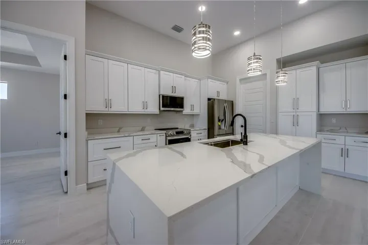 Kitchen featuring white cabinets, a sink, visible vents, stainless steel appliances, and a spacious island