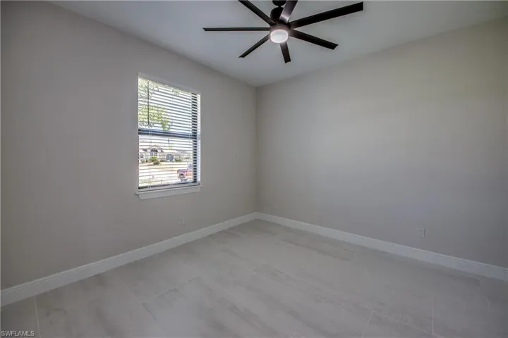 Unfurnished room with ceiling fan and baseboards