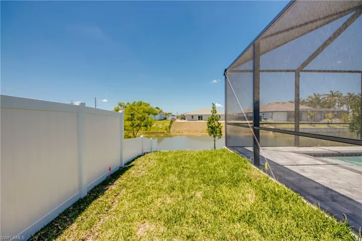 View of yard featuring glass enclosure, a water view, and fence