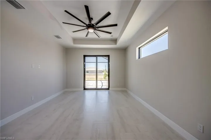 Empty room featuring baseboards, a tray ceiling, visible vents, and ceiling fan