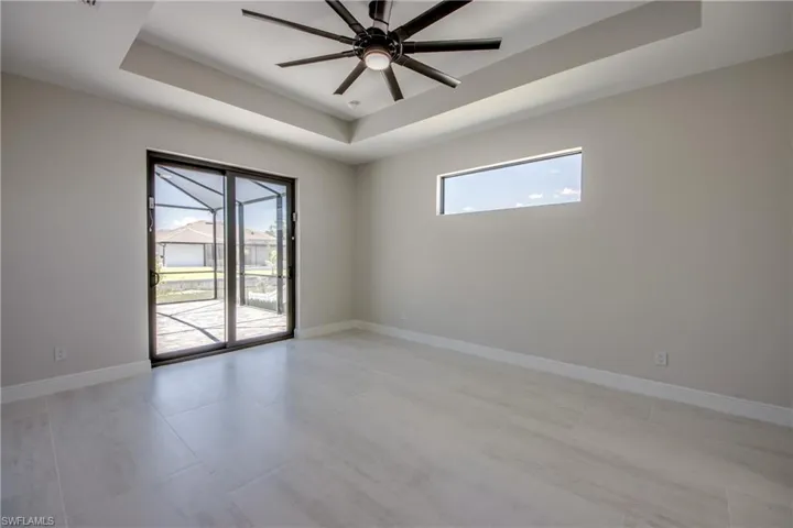 Unfurnished room with baseboards, a ceiling fan, a raised ceiling, and light tile patterned floors