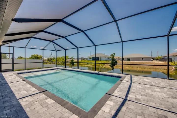 Pool featuring a patio, a water view, and glass enclosure
