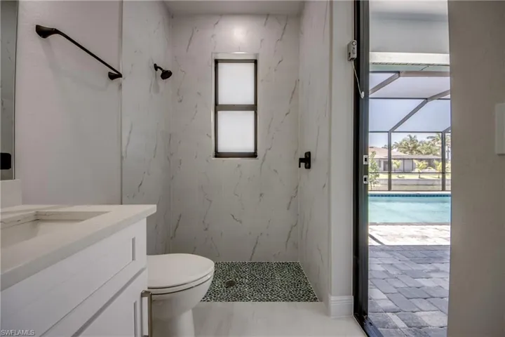 Bathroom featuring toilet, a marble finish shower, and vanity